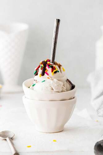 ice cream in a bowl with sprinkles and chocolate sauce drizzled on top